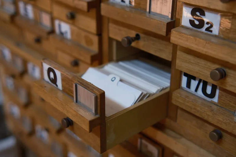 One drawer pulled open in a wall of honey-colored card-index cabinets, a packed row of filing cards