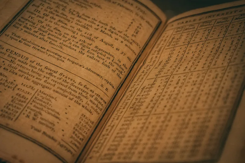 An open almanac on browned rag paper, the right-hand page ruled into a dense table of small figures